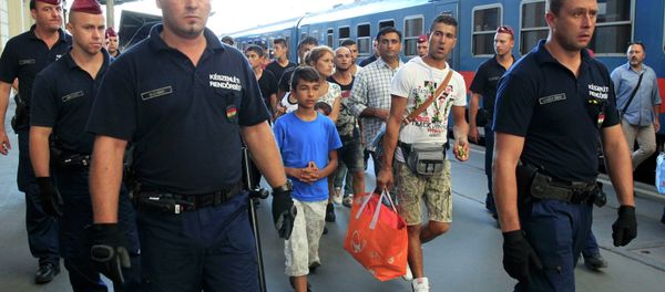 Hungarian police officers guard refugees to a regional train supposed to carry them to a nearby interim camp at a railways station in Budapest, Hungary September 2, 2015 - Sputnik International