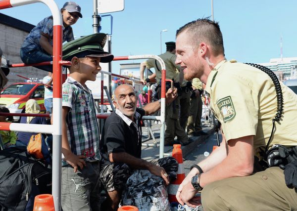 German police officer and a migrant boy joke with the officer's cap while migrants wait for a bus after their arrival at the main train station in Munich, southern Germany, September 1, 2015 German police officer and a migrant boy joke with the officer's cap while migrants wait for a bus after their arrival at the main train station in Munich, southern Germany, September 1, 2015 - Sputnik International