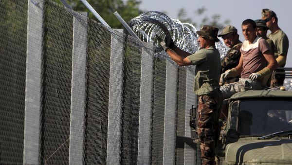 Hungarian soldiers adjust the razor wire on a fence near the town of Asotthalom, Hungary, August 30, 2015 Hungarian soldiers adjust the razor wire on a fence near the town of Asotthalom, Hungary, August 30, 2015 - Sputnik International