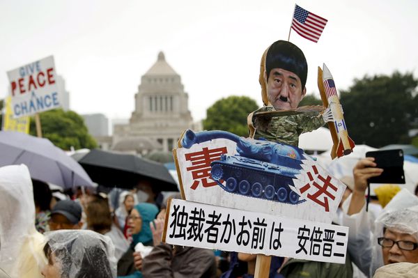 A protester holds a caricature cut-out of Japan's Prime Minister Shinzo Abe during a mass rally against his security bill outside the parliament in Tokyo August 30, 2015 - Sputnik International