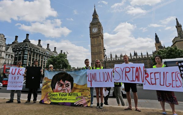 Protesters hold banners during an Amnesty International protest in Parliament Square to urge the British government to do more to help Syrian refugees, London, Saturday, July 11, 2015. - Sputnik International