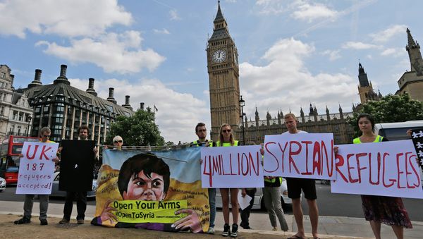 Protestors hold banners during an Amnesty International protest in Parliament Square to urge the British government to do more to help Syrian refugees, London, Saturday, July 11, 2015. Protestors hold banners during an Amnesty International protest in Parliament Square to urge the British government to do more to help Syrian refugees, London, Saturday, July 11, 2015. - Sputnik International