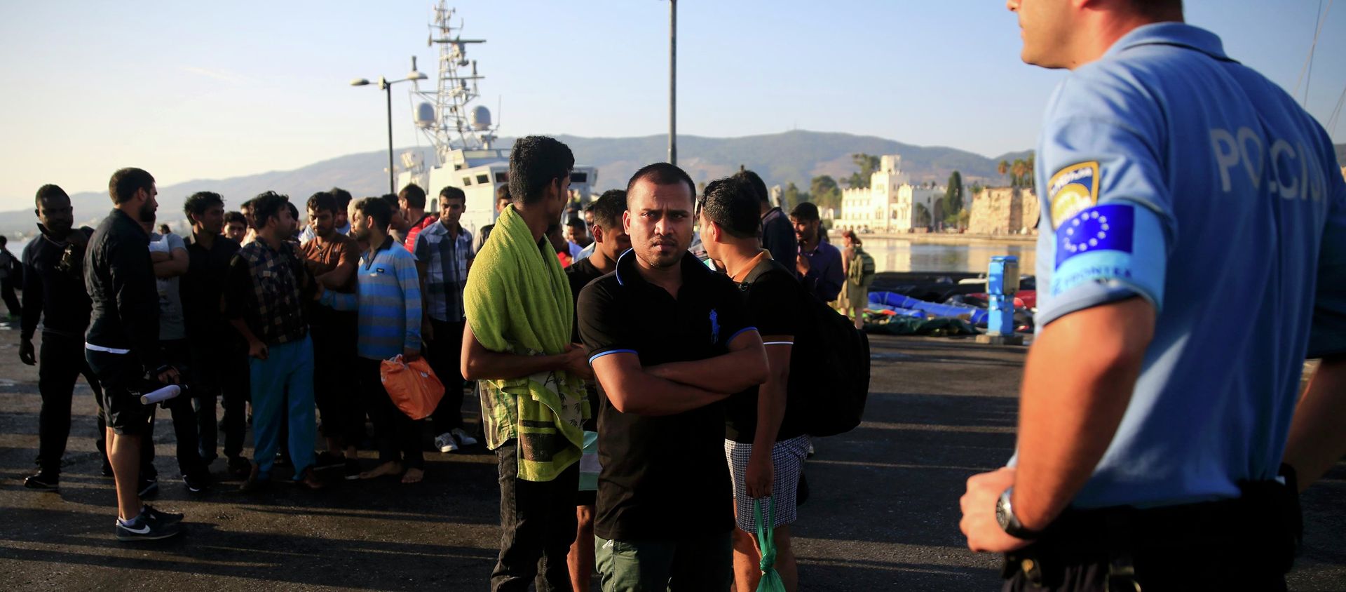 A migrant waits in line next to a Frontex officer (R) at the port of Kos, following a rescue operation off the Greek island of Kos, August 14, 2015 A migrant waits in line next to a Frontex officer (R) at the port of Kos, following a rescue operation off the Greek island of Kos, August 14, 2015 - Sputnik International, 1920, 02.11.2018