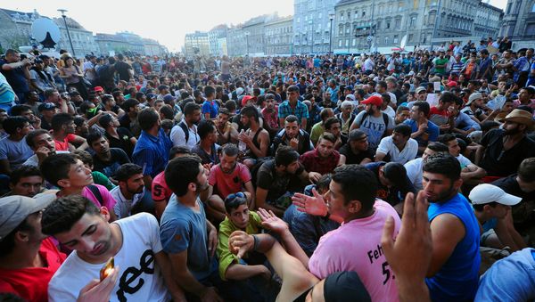 Migrants sit in front of the Keleti (East) railway station in Budapest on September 2, 2015 - Sputnik International