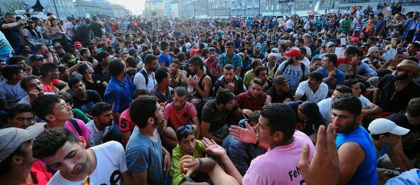 Migrants sit in front of the Keleti (East) railway station in Budapest on September 2, 2015 Migrants sit in front of the Keleti (East) railway station in Budapest on September 2, 2015 - Sputnik International