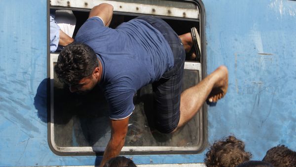 A migrant tries to board a train towards Serbia through a window, at the railway station in the southern Macedonian town of Gevgelija, on Saturday, Aug. 15, 2015 A migrant tries to board a train towards Serbia through a window, at the railway station in the southern Macedonian town of Gevgelija, on Saturday, Aug. 15, 2015 - Sputnik International