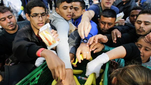 Migrants grab for food delivered by volunteers as they wait for registration at the reception center for refugees and asylum seekers in Berlin, Germany, Friday, Sept. 4, 2015 - Sputnik International