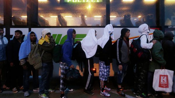 Migrants line up in front of a police bus at the Hungarian-Austrian border in Nickelsdorf, Austria, Saturday, Sept. 5, 2015, where they arrived from Budapest as Austria in the early-morning hours said it and Germany would let them in Migrants line up in front of a police bus at the Hungarian-Austrian border in Nickelsdorf, Austria, Saturday, Sept. 5, 2015, where they arrived from Budapest as Austria in the early-morning hours said it and Germany would let them in - Sputnik International