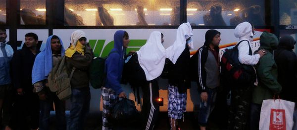 Migrants line up in front of a police bus at the Hungarian-Austrian border in Nickelsdorf, Austria, Saturday, Sept. 5, 2015, where they arrived from Budapest as Austria in the early-morning hours said it and Germany would let them in - Sputnik International