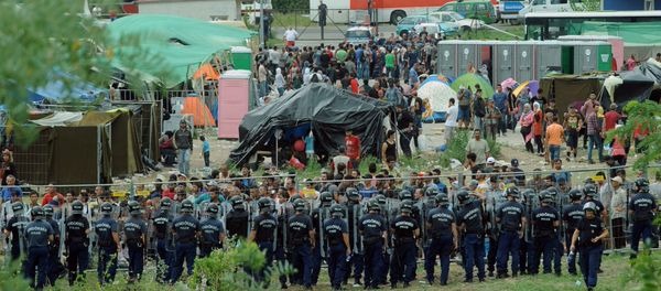 Police officers guard a local refugee camp in the village of Roszke at the Serbian-Hungarian border on September 4, 2015 where migrants are being held Police officers guard a local refugee camp in the village of Roszke at the Serbian-Hungarian border on September 4, 2015 where migrants are being held - Sputnik International