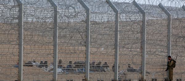 An Israeli soldier stands near the border fence between Israel and Egypt as African would-be immigrants sit on the other side near the Israeli village of Be'er Milcha, in this September 6, 2012 file photo - Sputnik International