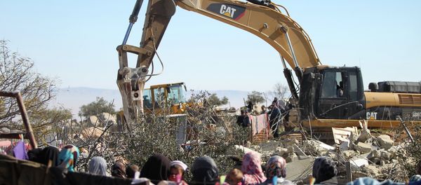 Palestinian women watch on as an Israeli army bulldozer with a demolition permit pulls down a house in the West Bank. Palestinian women watch on as an Israeli army bulldozer with a demolition permit pulls down a house in the West Bank. - Sputnik International