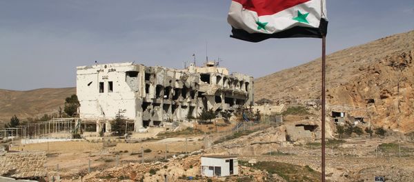 A Syrian flag on the background of ruined houses in the Syrian town of Maaloula, 55 km from Damascus, which was twice captured and looted by Jabhat al-Nusra militants. - Sputnik International