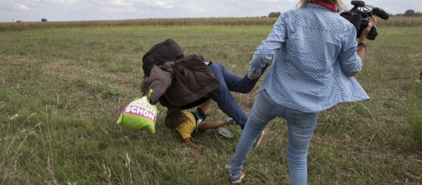 A refugee carrying a child falls after being tripped by a TV camerawoman while trying to escape from a collection point in Roszke village, Hungary. A refugee carrying a child falls after being tripped by a TV camerawoman while trying to escape from a collection point in Roszke village, Hungary. - Sputnik International
