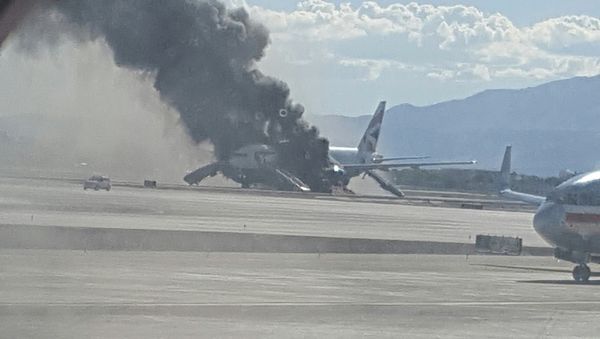 In this photo taken from the view of a plane window, smoke billows out from a plane that caught fire at McCarren International Airport, Tuesday, Sept. 8, 2015, in Las Vegas. An engine on the British Airways plane caught fire before takeoff, forcing passengers to escape on emergency slides. - Sputnik International