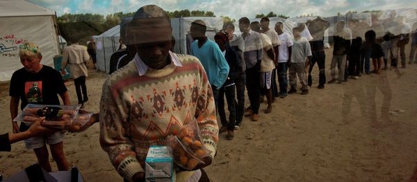 In this Tuesday, Aug. 4, 2015 file photo, migrants receive their food rations distributed by the Banque Alimentaire of Calais at a camp set in northern France. - Sputnik International
