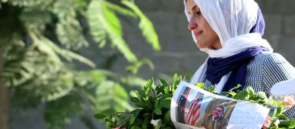 Libyan woman carries a wreath with a photo of U.S. Ambassador Chris Stevens on it as she and others gather to pay their respect to the victims of the Tuesday, Sept. 11, 2012 attack on the U.S. consulate, in Benghazi, Libya, Monday, Sept. 17, 2012 - Sputnik International