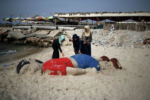 Palestinian girls put flowers on a sand sculpture by Indian artist Sudarsan Pattnaik depicting Syrian boy Alan Kurdi, a three-year-old boy who drowned off Turkey, on September 7, 2015, on Gaza city beach. - Sputnik International
