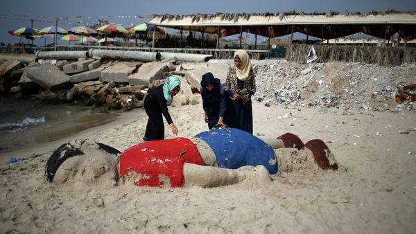 Palestinian girls put flowers on a sand sculpture depicting Syrian boy Aylan Kurdi, a three-year-old boy who drowned off Turkey, on September 7, 2015, on Gaza city beach - Sputnik International