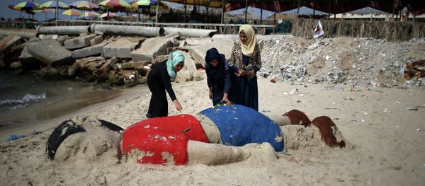 Palestinian girls put flowers on a sand sculpture by Indian artist Sudarsan Pattnaik depicting Syrian boy Aylan Kurdi, a three-year-old boy who drowned off Turkey, on September 7, 2015, on Gaza city beach Palestinian girls put flowers on a sand sculpture by Indian artist Sudarsan Pattnaik depicting Syrian boy Aylan Kurdi, a three-year-old boy who drowned off Turkey, on September 7, 2015, on Gaza city beach - Sputnik International