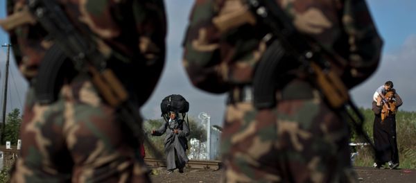 Hungarian army officers stand at the Serbian-Hungarian border as a Syrian refugee women crosses, near Roszke, southern Hungary, Saturday, Sept. 12, 2015 - Sputnik International