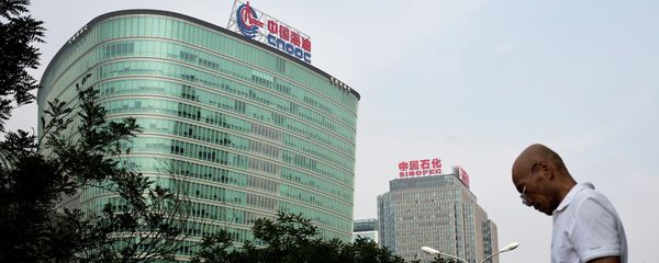 A man checks his mobile phone as he walks by buildings of China's state-owned companies, China National Offshore Oil Corp. (CNOOC), left, and China Petroleum & Chemical Corp. (Sinopec), in Beijing Monday, Sept. 14, 2015 A man checks his mobile phone as he walks by buildings of China's state-owned companies, China National Offshore Oil Corp. (CNOOC), left, and China Petroleum & Chemical Corp. (Sinopec), in Beijing Monday, Sept. 14, 2015 - Sputnik International
