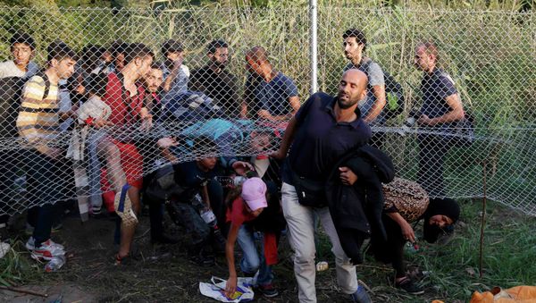 Migrants pass under a highway security fence as they try to find a new way to enter Hungary after Hungarian police sealed the border with Serbia near the village of Horgos, Serbia, September 14, 2015 Migrants pass under a highway security fence as they try to find a new way to enter Hungary after Hungarian police sealed the border with Serbia near the village of Horgos, Serbia, September 14, 2015 - Sputnik International