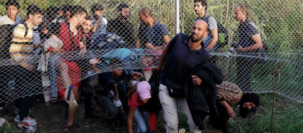 Migrants pass under a highway security fence as they try to find a new way to enter Hungary after Hungarian police sealed the border with Serbia near the village of Horgos, Serbia, September 14, 2015 Migrants pass under a highway security fence as they try to find a new way to enter Hungary after Hungarian police sealed the border with Serbia near the village of Horgos, Serbia, September 14, 2015 - Sputnik International