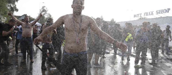 Migrants protest as Hungarian riot police fires tear gas and water cannon on the Serbian side of the border, near Roszke, Hungary September 16, 2015 - Sputnik International