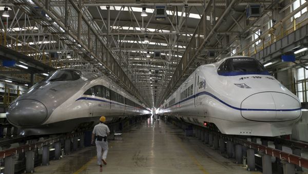 A worker walks between two bullet trains at a high speed railway maintenance station. - Sputnik International