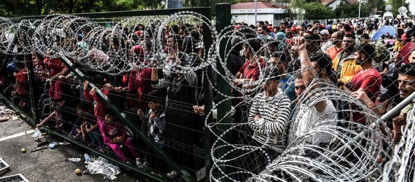 Refugees stand behind a fence at the Hungarian border with Serbia near the town of Horgos on September 16, 2015 Refugees stand behind a fence at the Hungarian border with Serbia near the town of Horgos on September 16, 2015 - Sputnik International