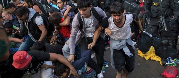 Migrants run as Hungarian riot police fires tear gas and water cannon at the border crossing with Serbia in Roszke, Hungary September 16, 2015. - Sputnik International