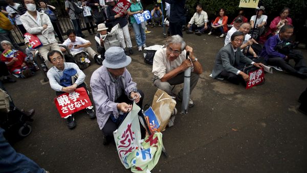 Protesters sitting on the ground with placards take part in a rally against Japan's Prime Minister Shinzo Abe's security bill and his administration in front of the parliament in Tokyo, September 18, 2015. Protesters sitting on the ground with placards take part in a rally against Japan's Prime Minister Shinzo Abe's security bill and his administration in front of the parliament in Tokyo, September 18, 2015. - Sputnik International