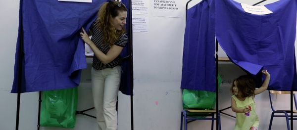 A woman casts her vote as her three-year old daughter plays in an election booth at a polling station in Athens, Sunday, Sept. 20, 2015 - Sputnik International