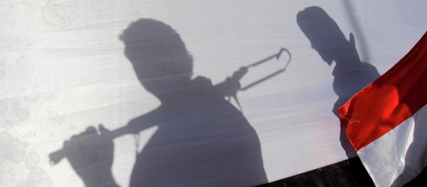 In this Thursday, April 16, 2015 photo, The shadow of Shiite rebels, known as Houthis, are cast on a large representation of the Yemeni flag as they attend a demonstration against an arms embargo imposed by the U.N. Security Council on Houthi leaders, in Sanaa, Yemen. - Sputnik International