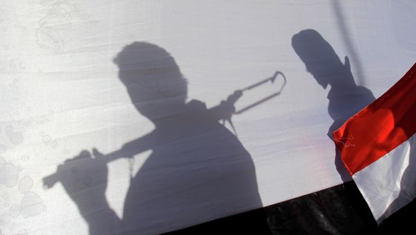 In this Thursday, April 16, 2015 photo, The shadow of Shiite rebels, known as Houthis, are cast on a large representation of the Yemeni flag as they attend a demonstration against an arms embargo imposed by the U.N. Security Council on Houthi leaders, in Sanaa, Yemen. - Sputnik International