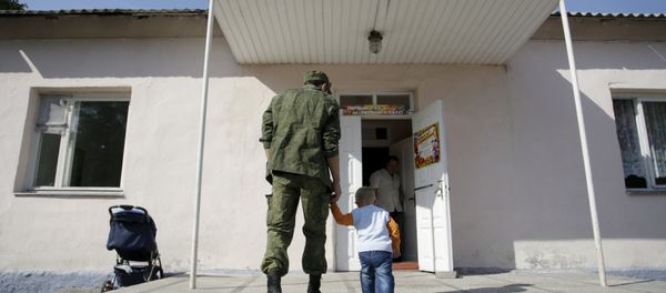 A man wearing a camouflage uniform walks with a child as they enter a school on the start of the new school year in Donetsk, Ukraine, September 1, 2015 - Sputnik International