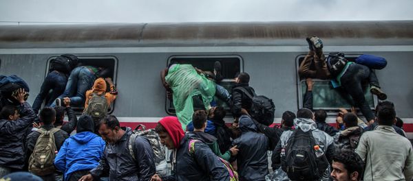 Migrants and refugees board a train by climbing through the windows as they try to avoid a police barrier at the station in Tovarnik, Croatia, Sunday, Sept. 20, 2015 - Sputnik International