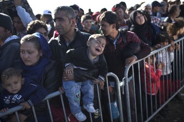 A Syrian refugee man holding his sleeping son, rests on the ground after spending the night at a collection point in the truck parking lot of the former border station on the Austrian side of the Hungarian-Austrian border near Nickelsdorf, Austria, Wednesday, Sept. 23, 2015. A Syrian refugee man holding his sleeping son, rests on the ground after spending the night at a collection point in the truck parking lot of the former border station on the Austrian side of the Hungarian-Austrian border near Nickelsdorf, Austria, Wednesday, Sept. 23, 2015. - Sputnik International