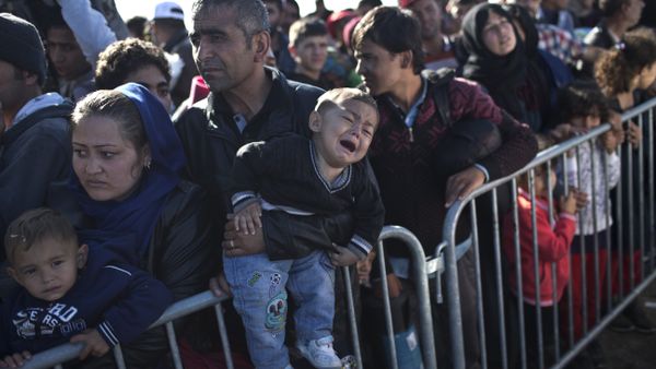 A Syrian refugee man holding his sleeping son, rests on the ground after spending the night at a collection point in the truck parking lot of the former border station on the Austrian side of the Hungarian-Austrian border near Nickelsdorf, Austria, Wednesday, Sept. 23, 2015. - Sputnik International