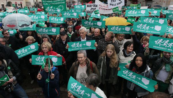 People take part in a demonstration in support of migrants holding up placards saying 'Refugees welcome' in front of the Mikolaj Kopernik's statue in Warsaw, Poland, Saturday, Sept. 12, 2015. - Sputnik International