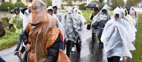 Refugees walked in heavy rain from a public transport centre to Lappia-building refugee reception centre in Tornio, northwestern Finland Refugees walked in heavy rain from a public transport centre to Lappia-building refugee reception centre in Tornio, northwestern Finland - Sputnik International