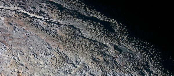 Rounded and bizarrely textured mountains, informally named the Tartarus Dorsa, rise up along Pluto’s day-night terminator and show intricate but puzzling patterns of blue-gray ridges and reddish material in between. Rounded and bizarrely textured mountains, informally named the Tartarus Dorsa, rise up along Pluto’s day-night terminator and show intricate but puzzling patterns of blue-gray ridges and reddish material in between. - Sputnik International