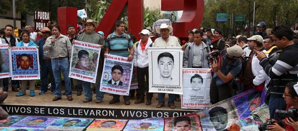 Relatives hold pictures of some of the 43 missing students of Ayotzinapa College Raul Isidro Burgos during a march to mark the first anniversary of their disappearance, in Mexico City, September 26, 2015 - Sputnik International