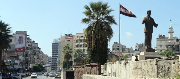A man rides his bike past a statue of late Syrian president Hafez al-Assad, father of current President Bashar al-Assad, in the Syrian coastal city of Latakia on September 24, 2015 - Sputnik International