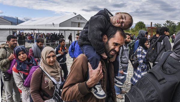 Migrants and refugees stand in line as they wait to board a train at the registration camp after crossing the Macedonian-Greek border near Gevgelija on September 28, 2015 - Sputnik International