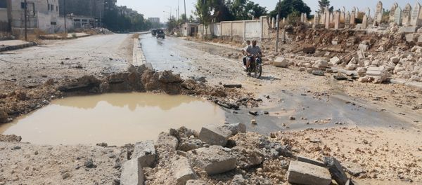 Residents ride a motorbike past a crater filled with water in Aleppo's al-Shaar neighborhood, Syria September 28, 2015 Residents ride a motorbike past a crater filled with water in Aleppo's al-Shaar neighborhood, Syria September 28, 2015 - Sputnik International