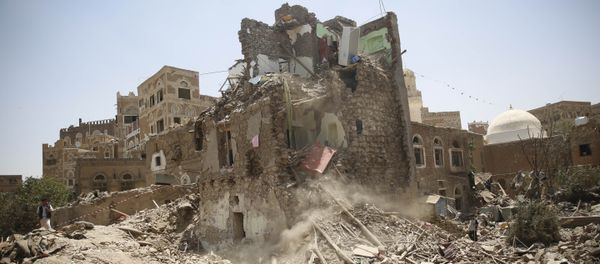A man, left, stands guard amid the rubble of a house damaged in a Saudi-led airstrike in Sanaa, Yemen, Saturday, Sept. 19, 2015. - Sputnik International
