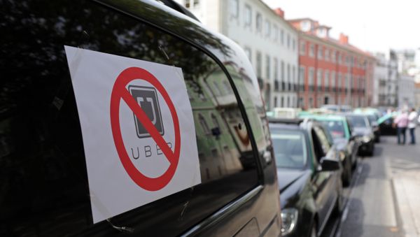 Taxis with signs against the Uber ride-hailing service clog a street in Lisbon while moving at a slow pace in protest, Tuesday, Sept. 8 2015 - Sputnik International