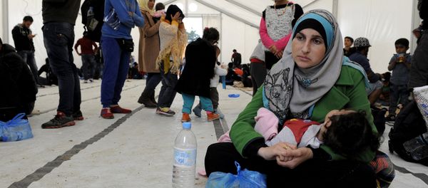 A migrant woman holds a baby inside a large tent set by NGOs, as refugees and migrants wait to cross Greece's border with Macedonia near the Greek village of Idomeni, September 26, 2015 - Sputnik International